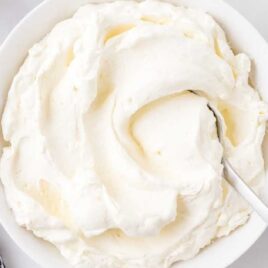 close up overhead shot of a bowl of stabilized whipped cream with a spoon