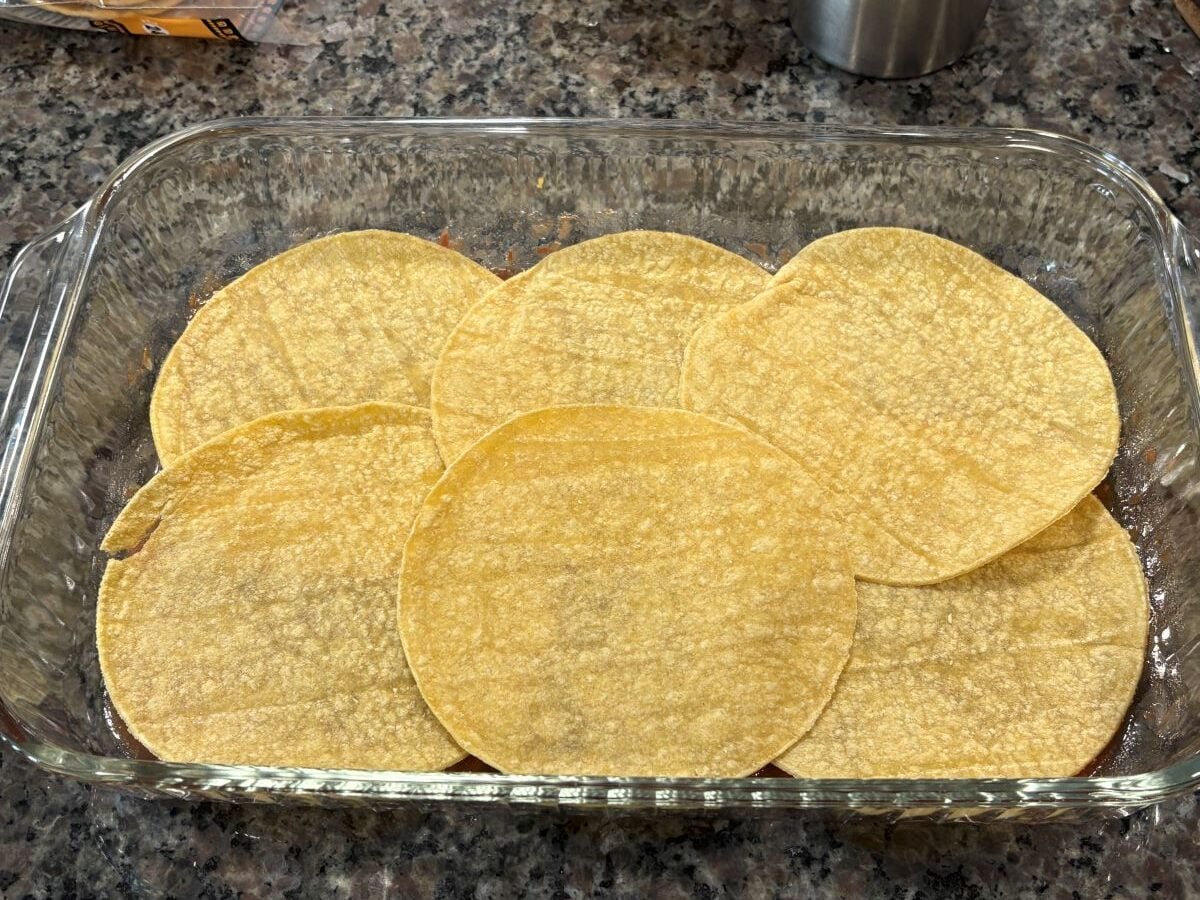 tortillas layered in the bottom of a baking dish