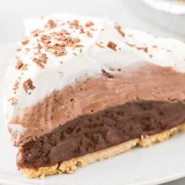 close up shot of a slice of chocolate pudding pie garnished with chocolate shavings on a plate