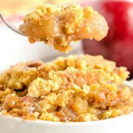 close up shot of a bowl of Caramel Apple Dump Cake with a piece being taken out with a fork