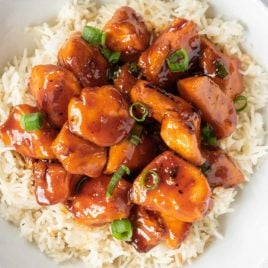 A plate of food with rice meat and vegetables, with Bourbon chicken