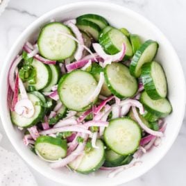 A bowl of salad on a plate, with Cucumber