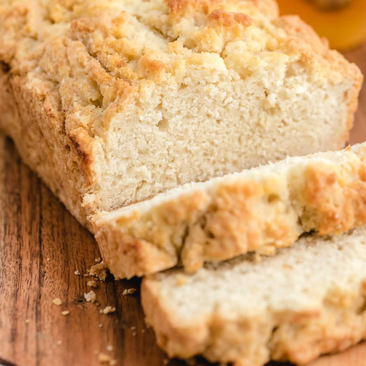 close up shot of a loaf of Beer Bread with slices taken out of it on a wooden board