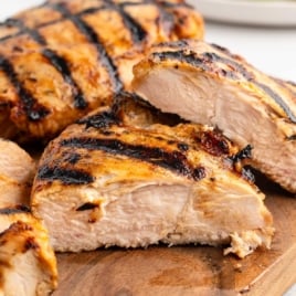 Close-up of sliced grilled chicken breast on a cutting board, showing juicy texture and grill marks.