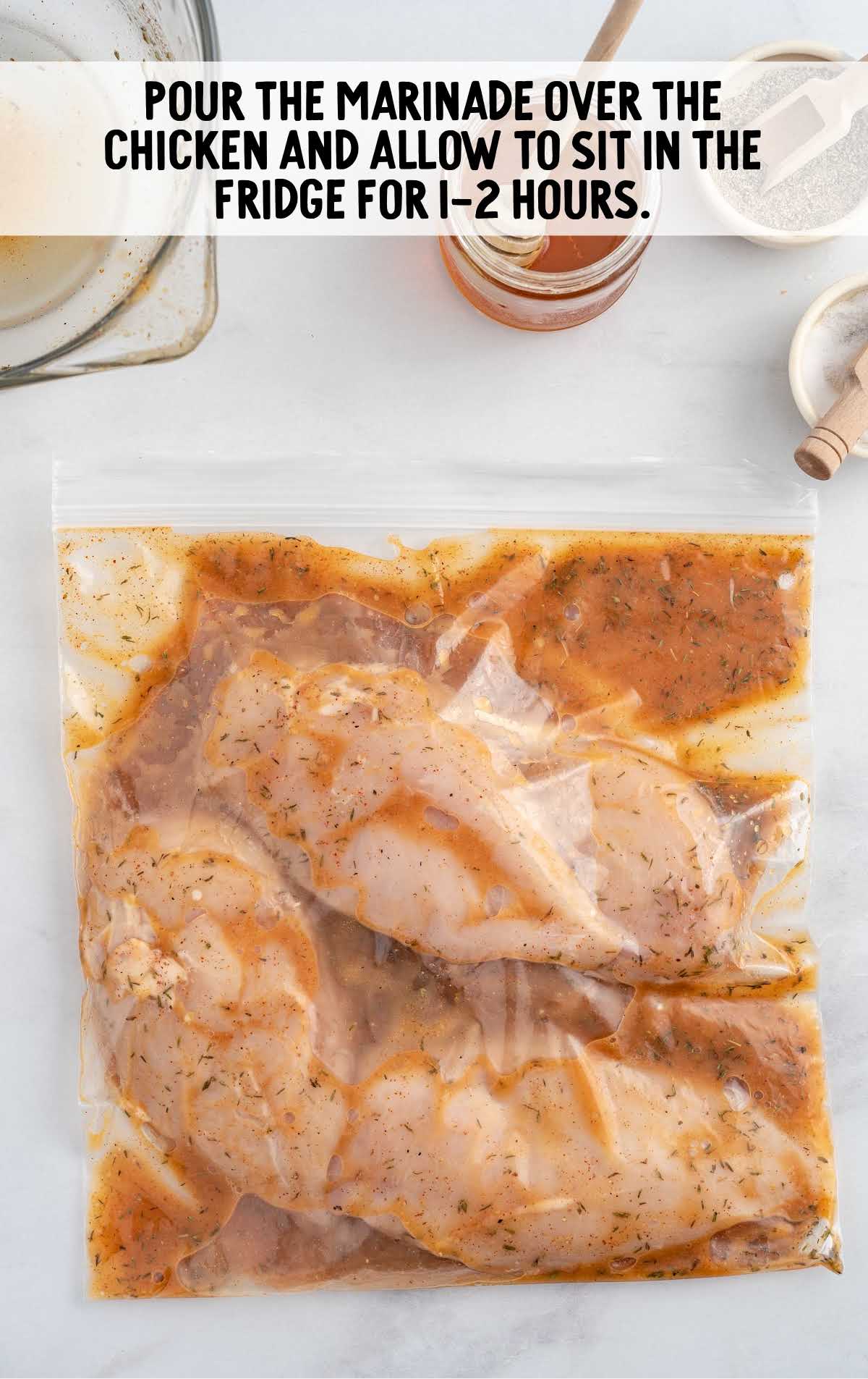 marinade ingredients poured over the chicken in a ziploc bag