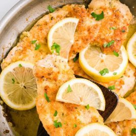 close up overhead shot of Lemon Chicken with lemon slices and garnished with parsley in a skillet