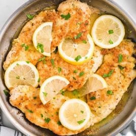 close up overhead shot of Lemon Chicken with lemon slices and garnished with parsley in a skillet