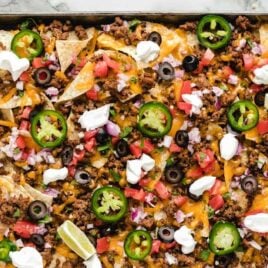 close up overhead shot of a sheet pan of Sheet Pan Nachos garnished with toppings