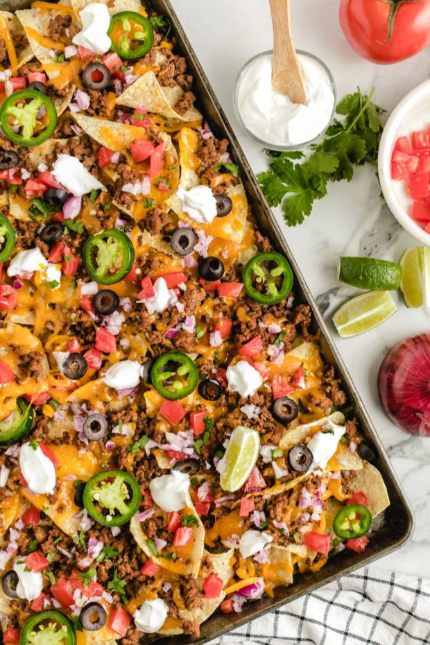 A box filled with different types of food on a table, with Nachos and Sheet pan