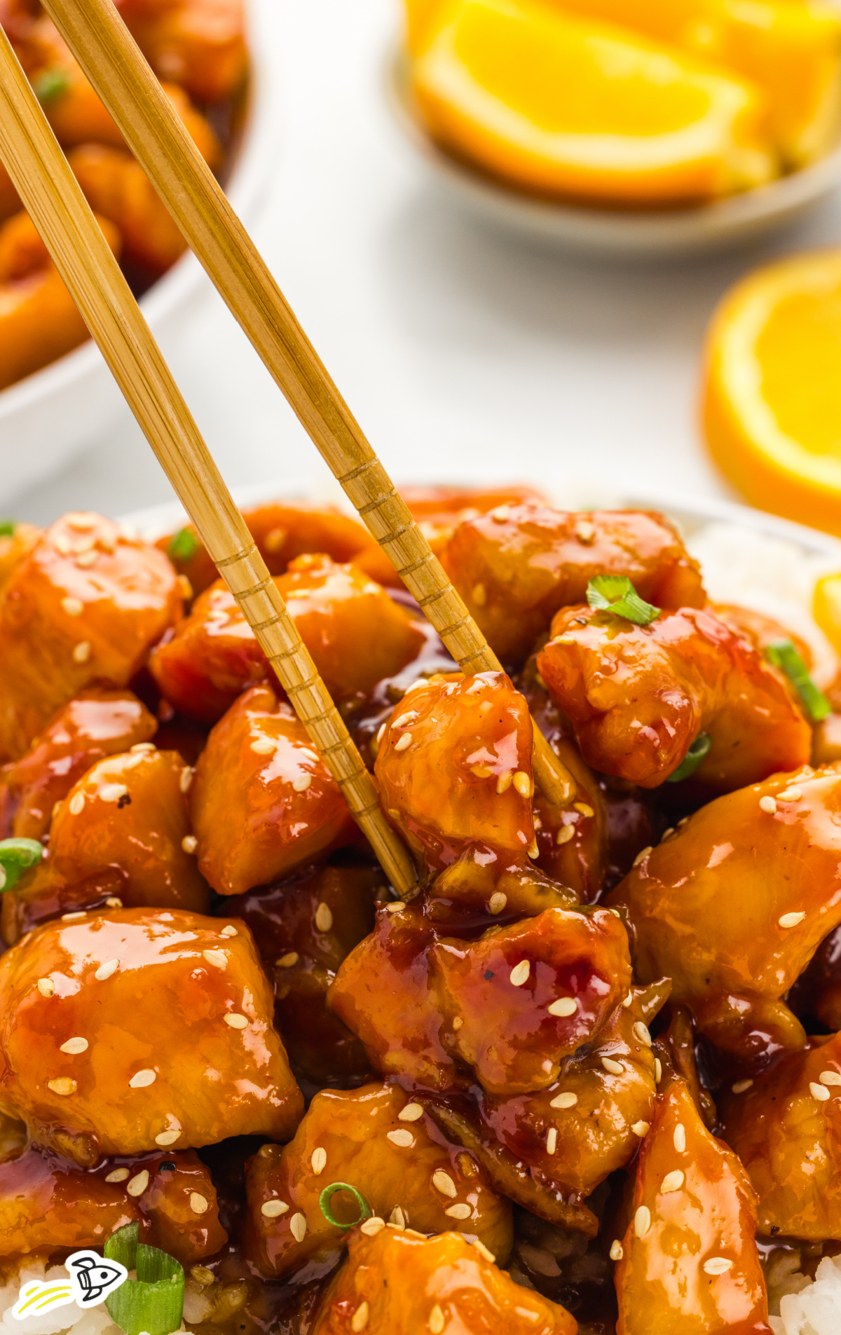 A serving of orange chicken with chopsticks.