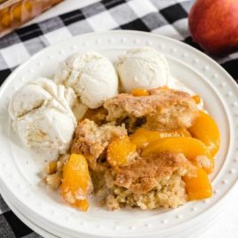 a piece of Peach Cobbler with vanilla ice cream on a plate