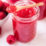 close up shot of a jar of Raspberry Freezer Jam with a bowl of raspberries