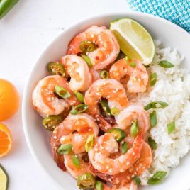close up overhead shot of Spicy Garlic Shrimp served with white rice topped with green onions and a slice of lime in a bowl