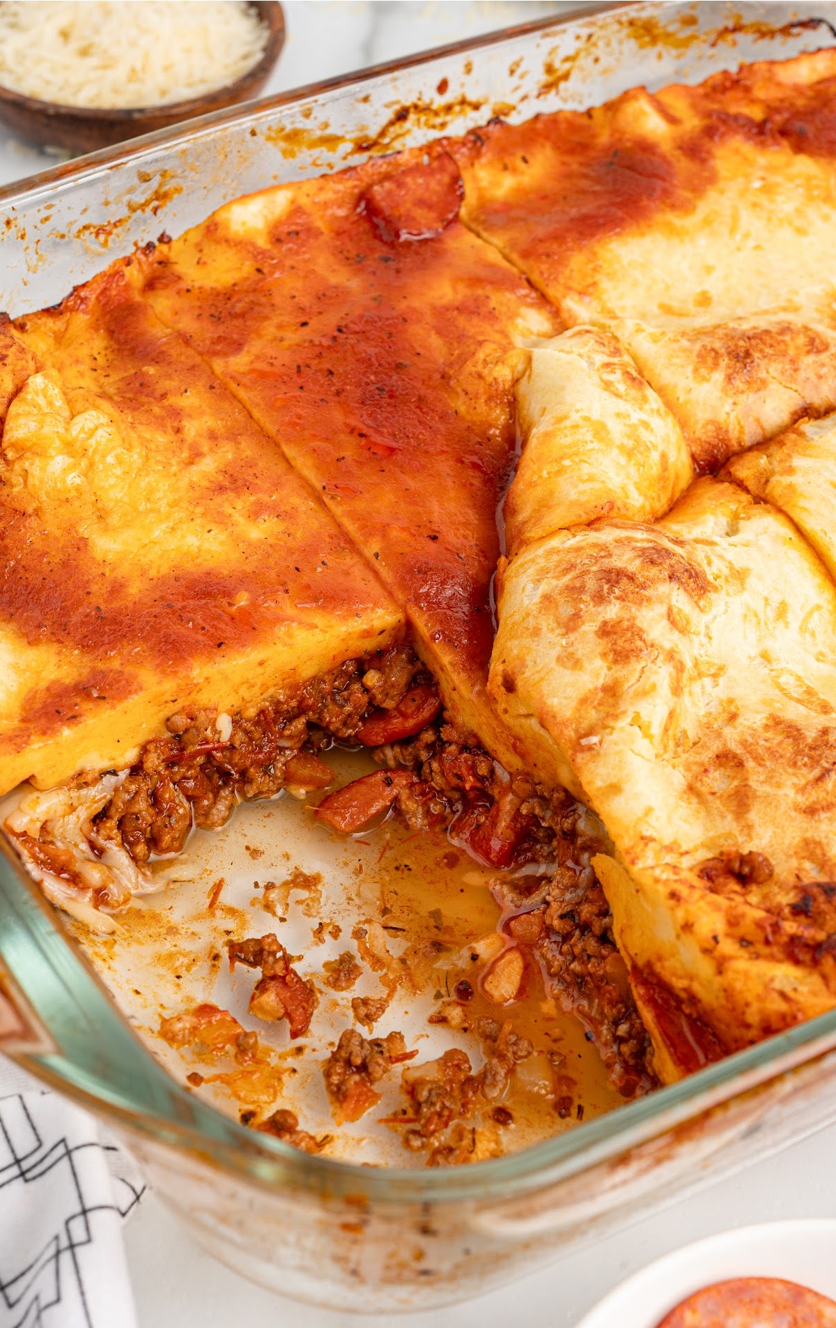 A casserole dish with a piece of the pizza missing.