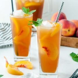 A close up of a glass of orange juice, with Iced tea