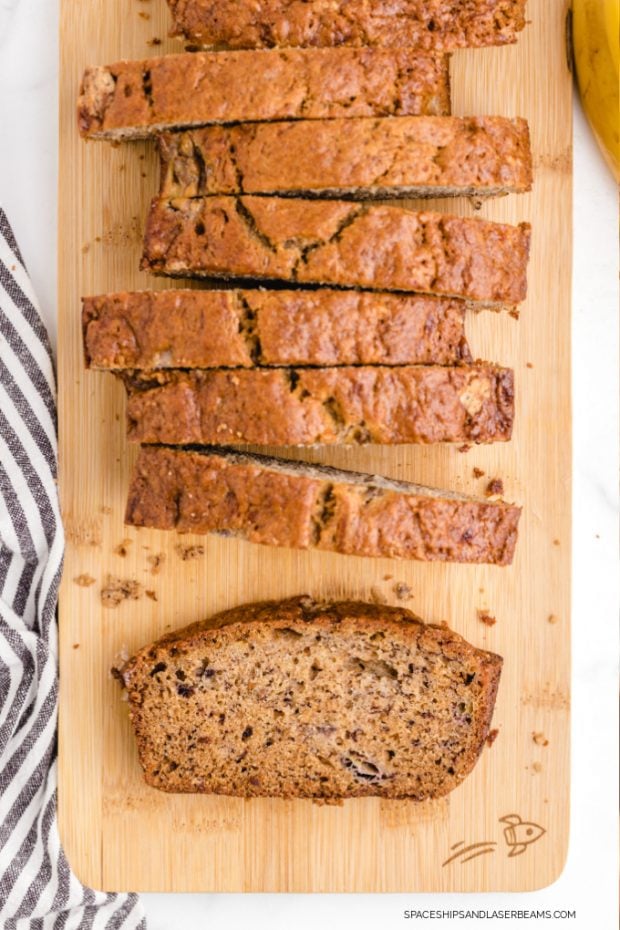 a loaf of banana bread sliced into pieces sitting on a wood cutting board