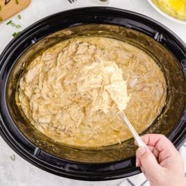 spoon scooping out chicken and gravy from crockpot