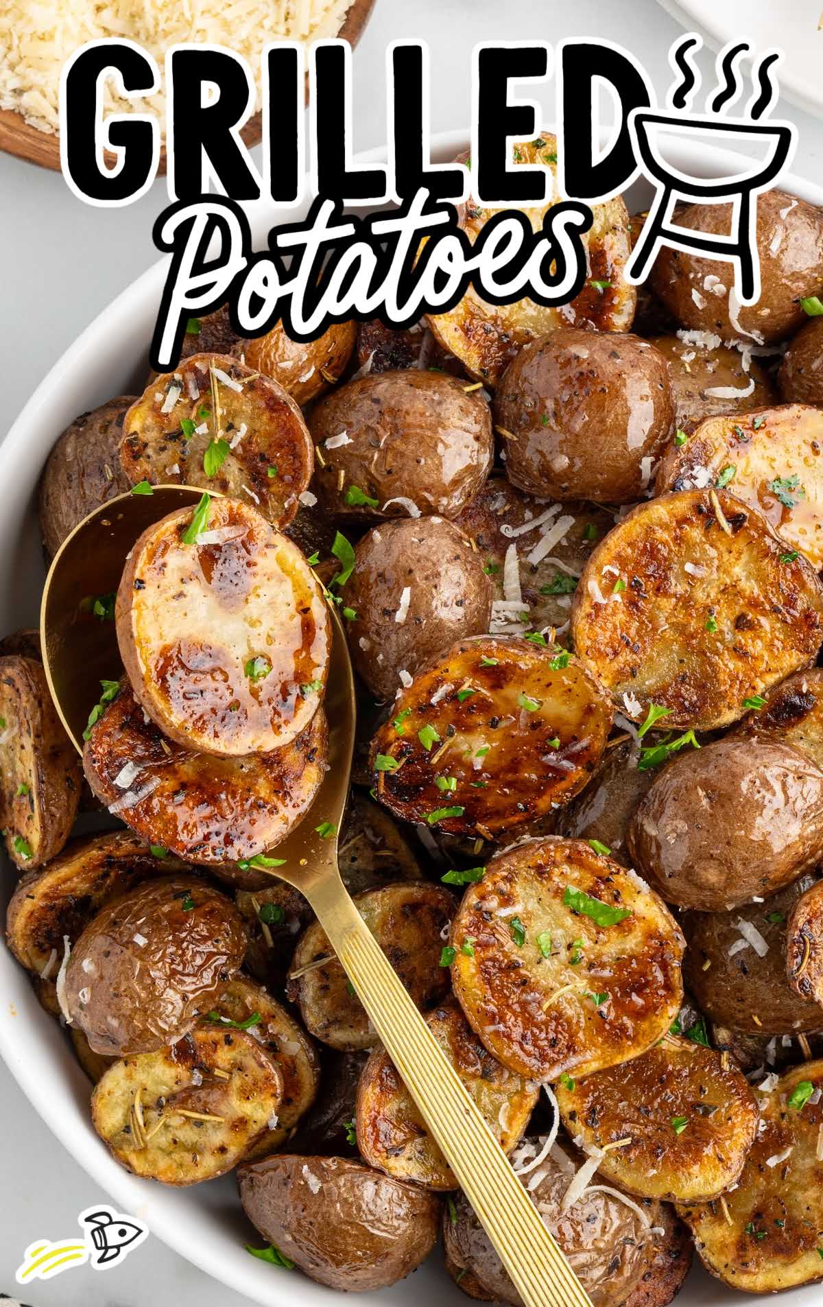 Bowl of grilled potatoes with golden crispy edges, garnished with parsley and shredded cheese