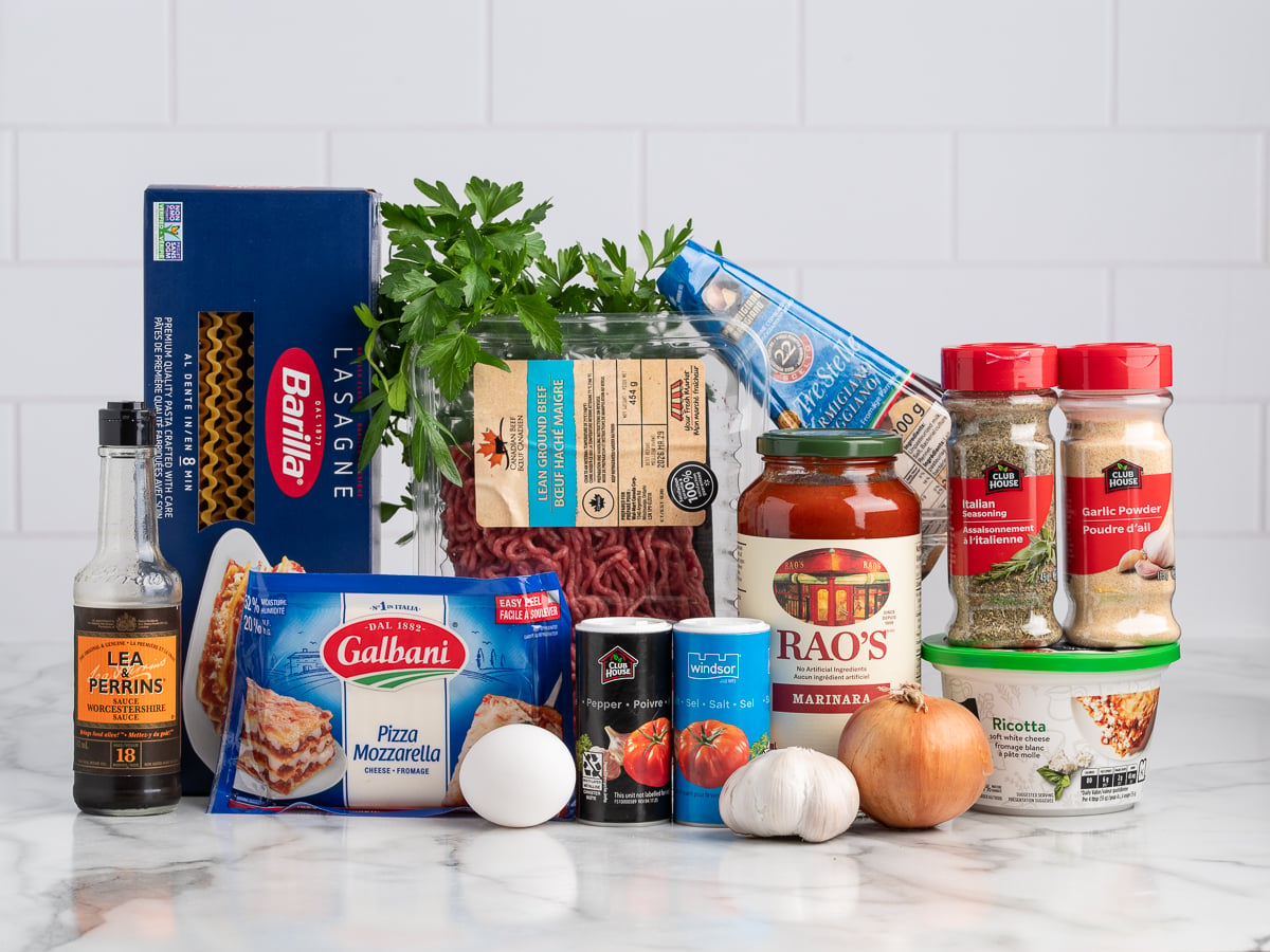 Assorted lasagna ingredients on a countertop, perfect for creating classic lasagna or trying a delicious Lasagna Roll Ups recipe with noodles, ground beef, tomato sauce, ricotta, mozzarella, parmesan, garlic, onion, egg, and seasonings.