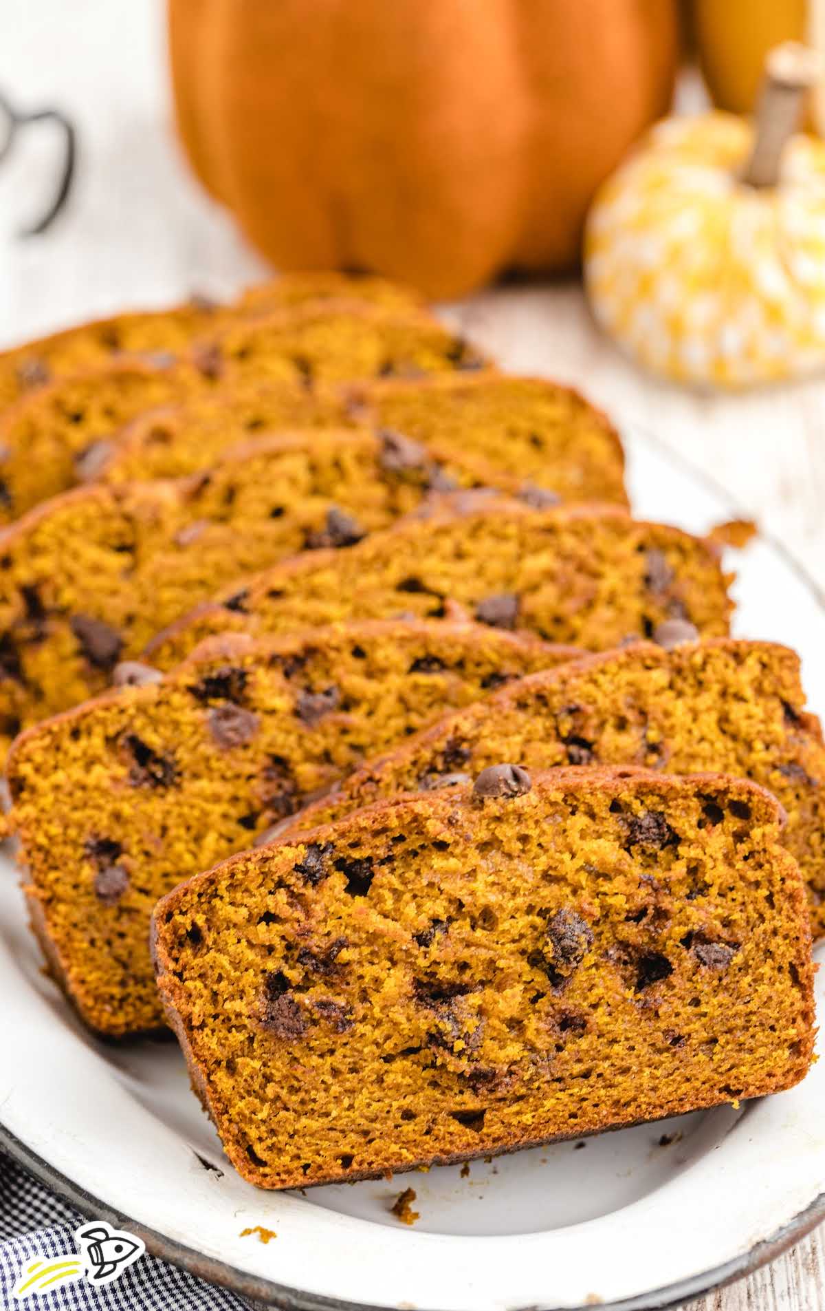 Plate of pumpkin chocolate chip bread slices with pumpkins in the background.