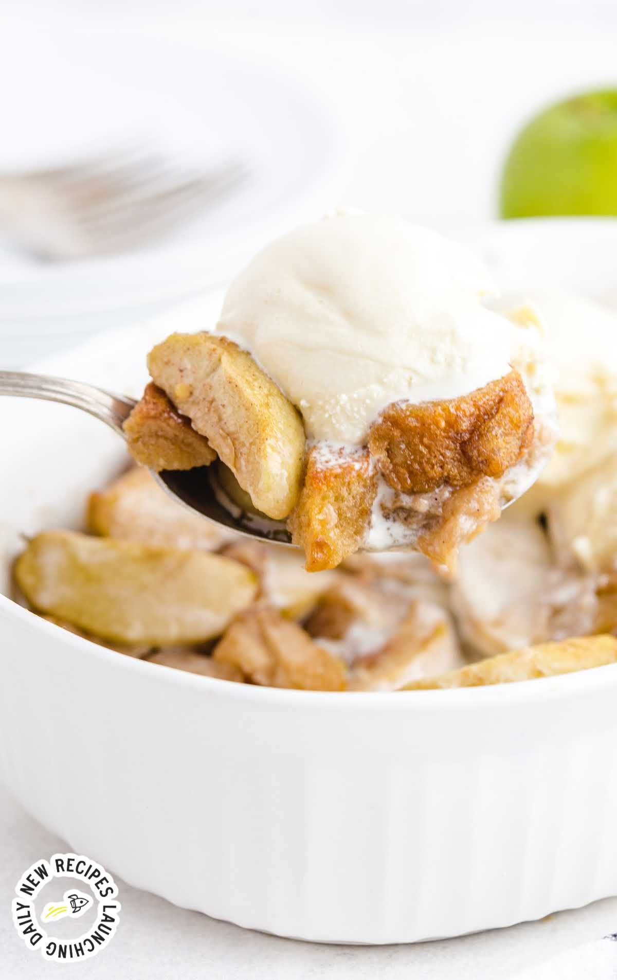 close up shot of grandma's apple betty in a white casserole pan with a 3 scoops of ice cream on the top