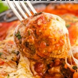 close up shot of meatball parmesan with parmesan cheese and pasta sauce on a fork