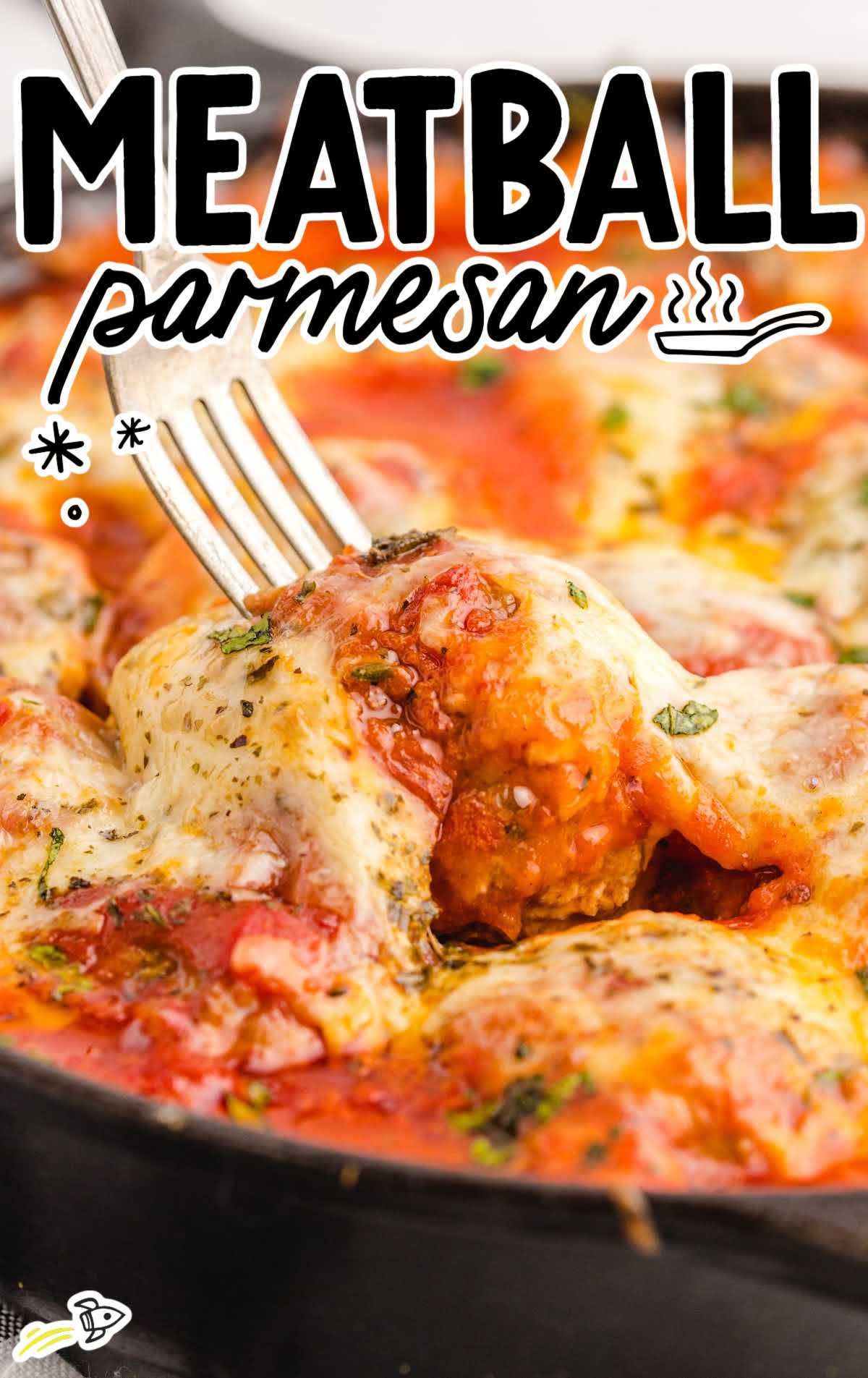 Close-up of melted mozzarella and marinara-covered meatball being lifted from skillet with fork, labeled 'Meatball Parmesan.'