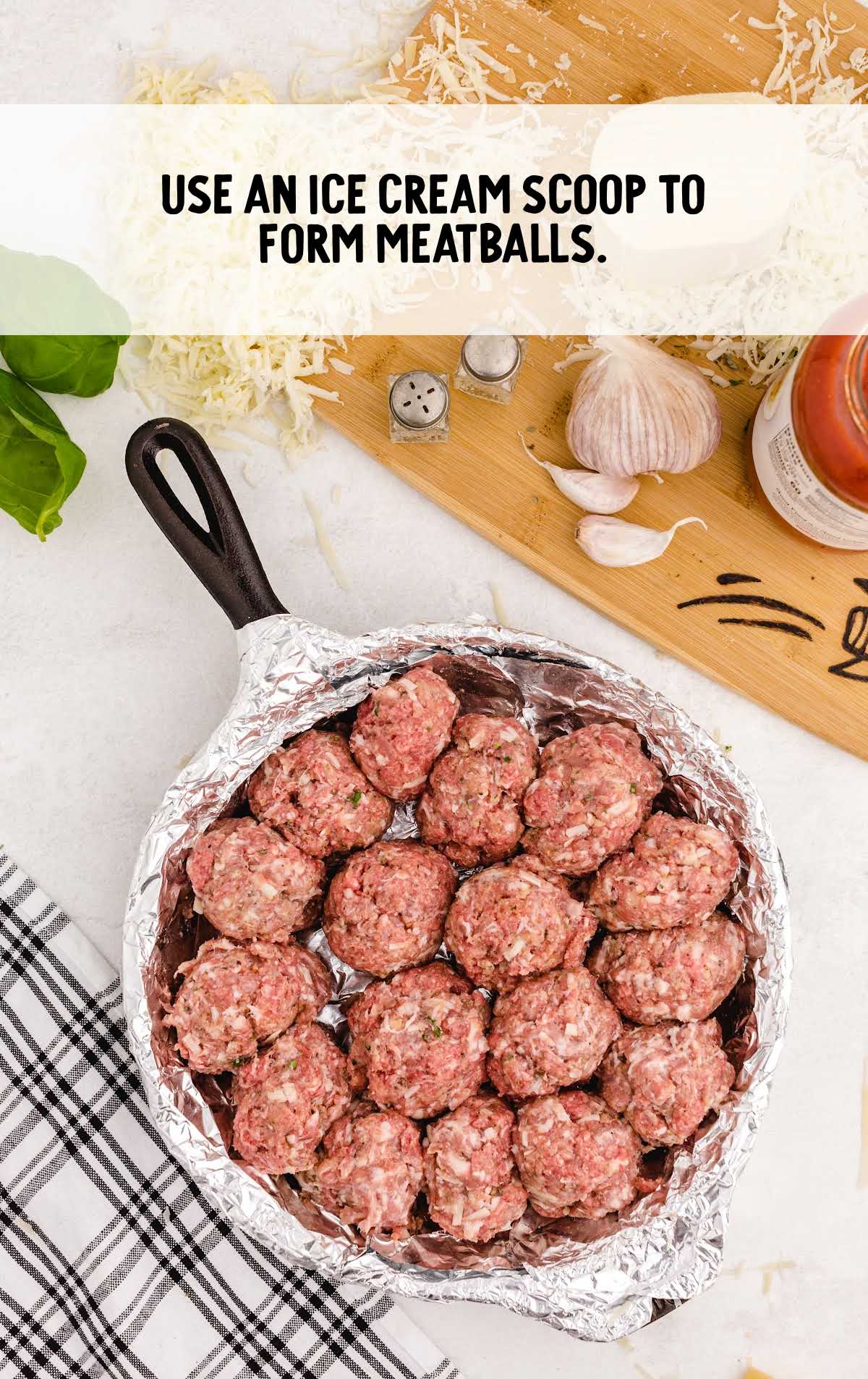 Raw meatballs formed in a foil-lined skillet with overlay text: 'Use an ice cream scoop to form meatballs.'