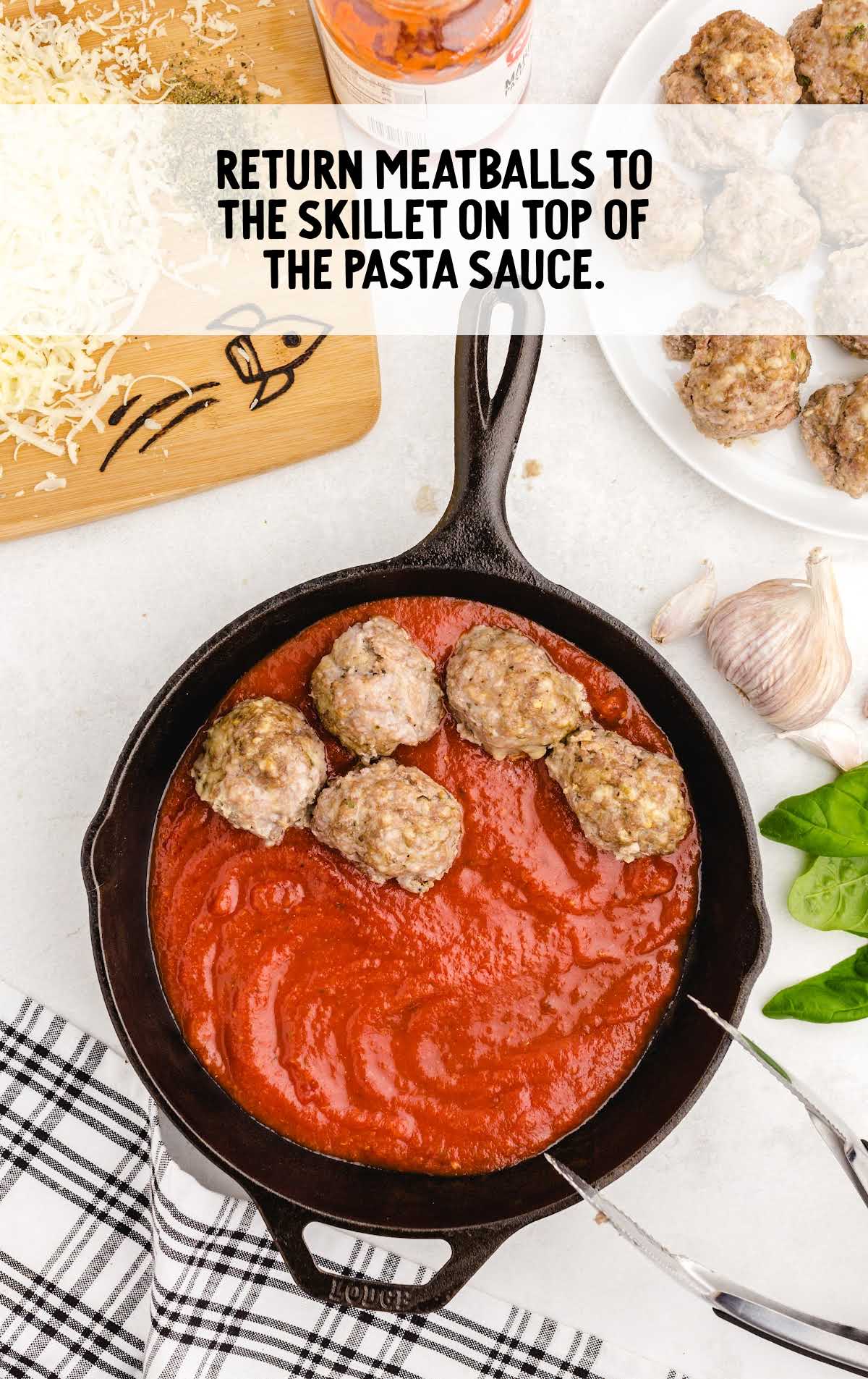 Skillet of marinara sauce topped with cooked meatballs, with overlay text: 'Return meatballs to the skillet on top of the pasta sauce.'