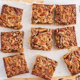 overhead shot of Pecan Pie Bars on a wooden board with a bowl of pecans