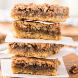 close up shot of Pecan Pie Bars stacked on top of each other on a wooden board