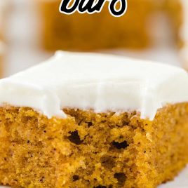 close up shot of pumpkin bars topped with cream cheese frosting with a bite taken out of it