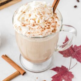 close up shot of pumpkin spice latte in glass mug with whipped cream