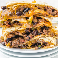 close up shot of sheet pan quesadillas stacked on top of each other on a white plate