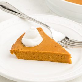 slice of crustless pumpkin with a dollop of cream on a white plate with a fork