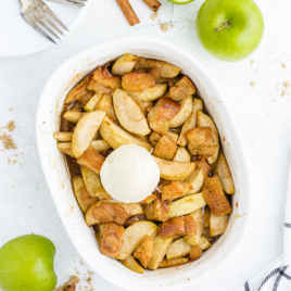 grandma's apple betty in a white casserole pan with a scoop of ice cream on top
