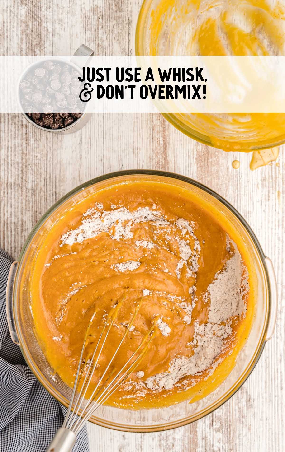 Mixing pumpkin chocolate chip bread batter in a bowl with a whisk.