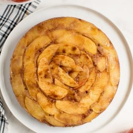 Baked Upside Down Apple Cake on a Platter with Fresh Apples on the Side