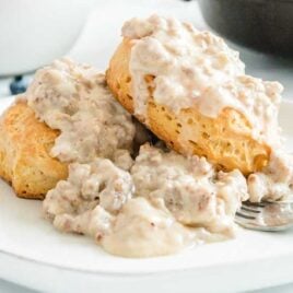 close up shot of a plate of biscuits topped with sausage gravy