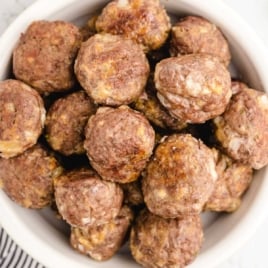 Close-up shot of baked homemade meatballs stacked in a bowl, showing golden brown texture.