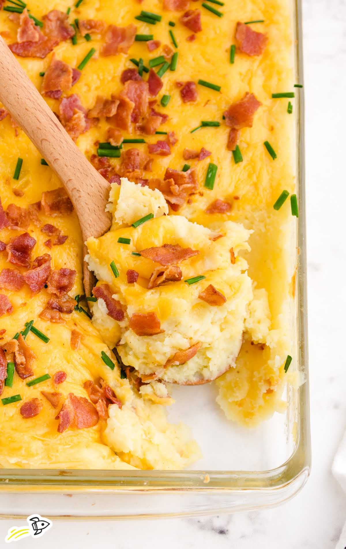 close up shot of mashed potato casserole with bacon bits on the top in a clear pan