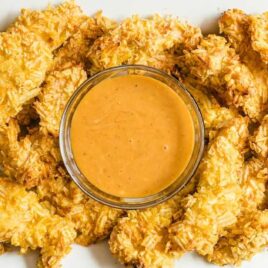 overhead shot of a plate of Potato Chip Chicken Tenders with a cup of dipping sauce