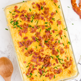 mashed potato casserole in a clear pan with bacon bits on top