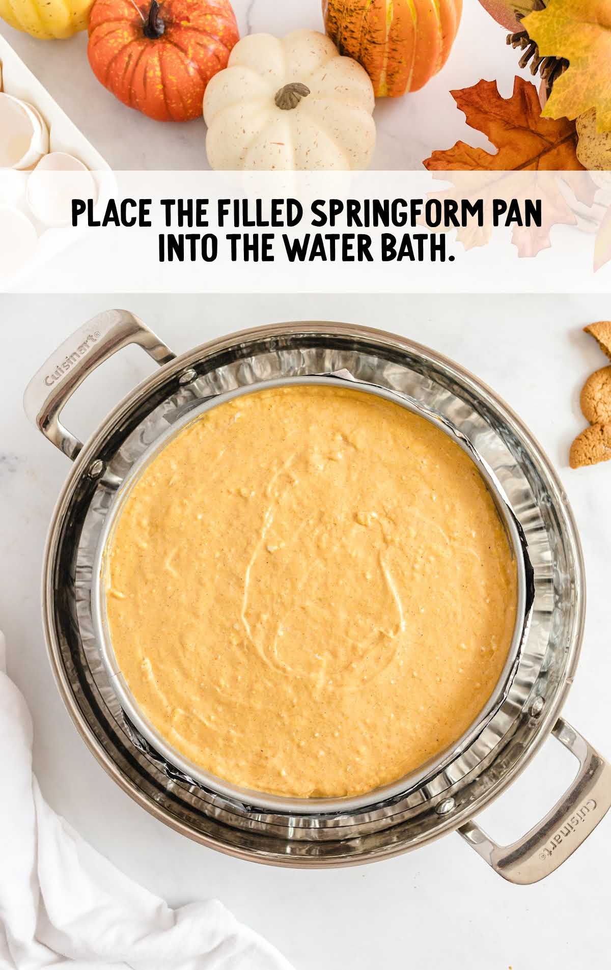 Pumpkin cheesecake batter in a springform pan placed inside a water bath, ready for baking.