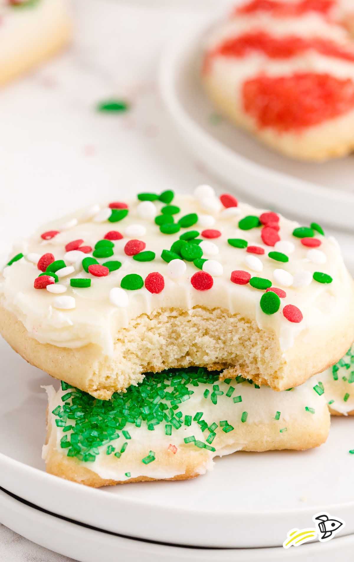 close up shot of Christmas Sugar Cookies on top of each other on a plate with one having a bite taken out of it