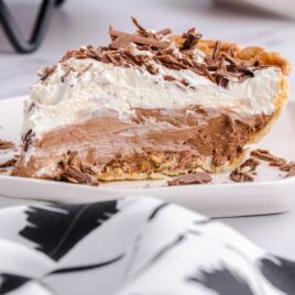 close up shot of a slice of french silk pie garnished with chopped chocolate on a white plate