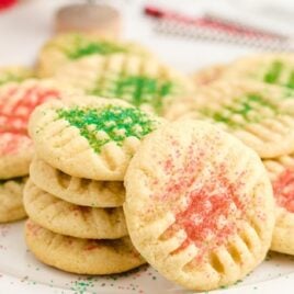close up shot of grandma's christmas sugar cookies piled on top of each other on a white plate