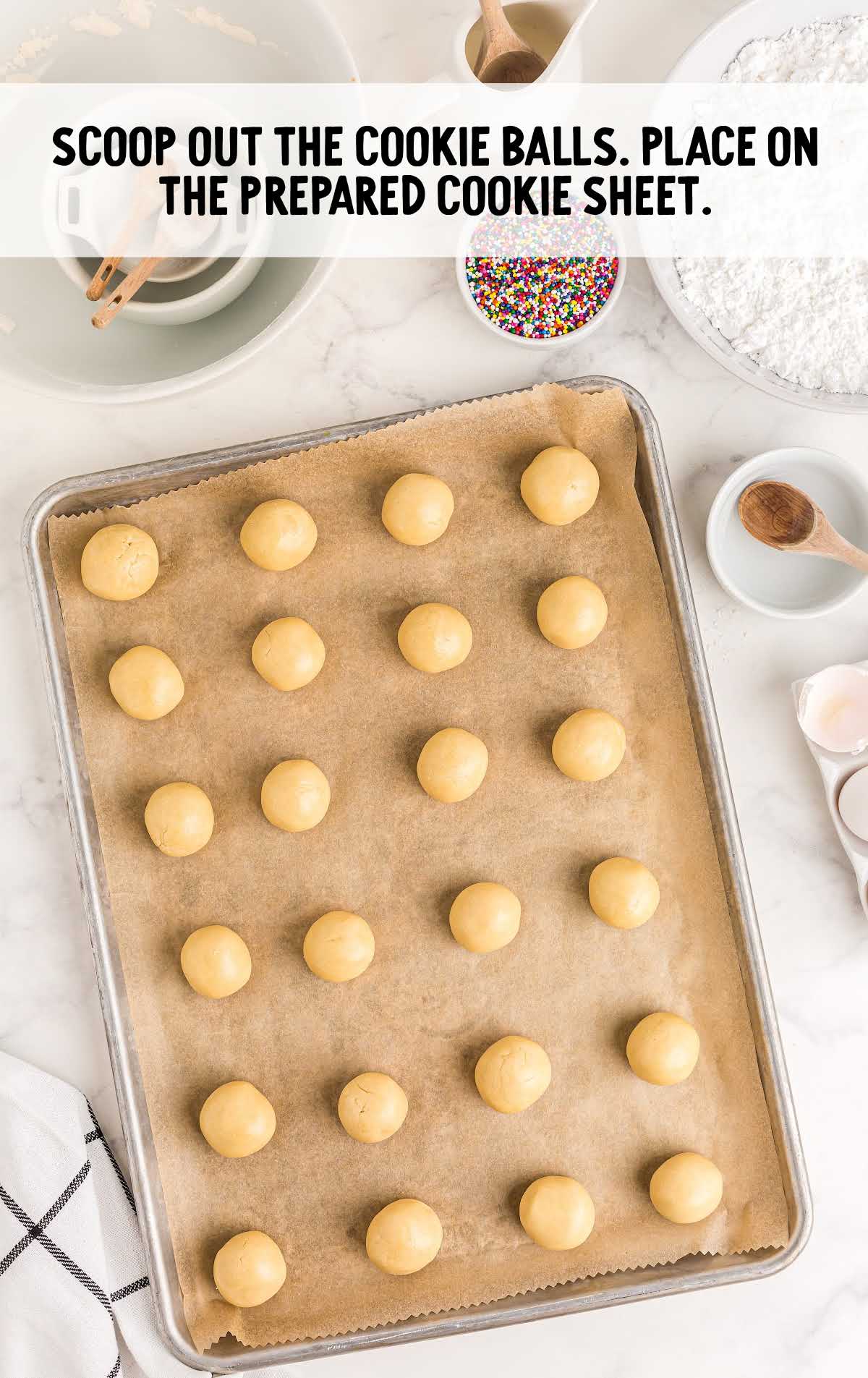 cookie balls scooped out and placed on a cookie sheet