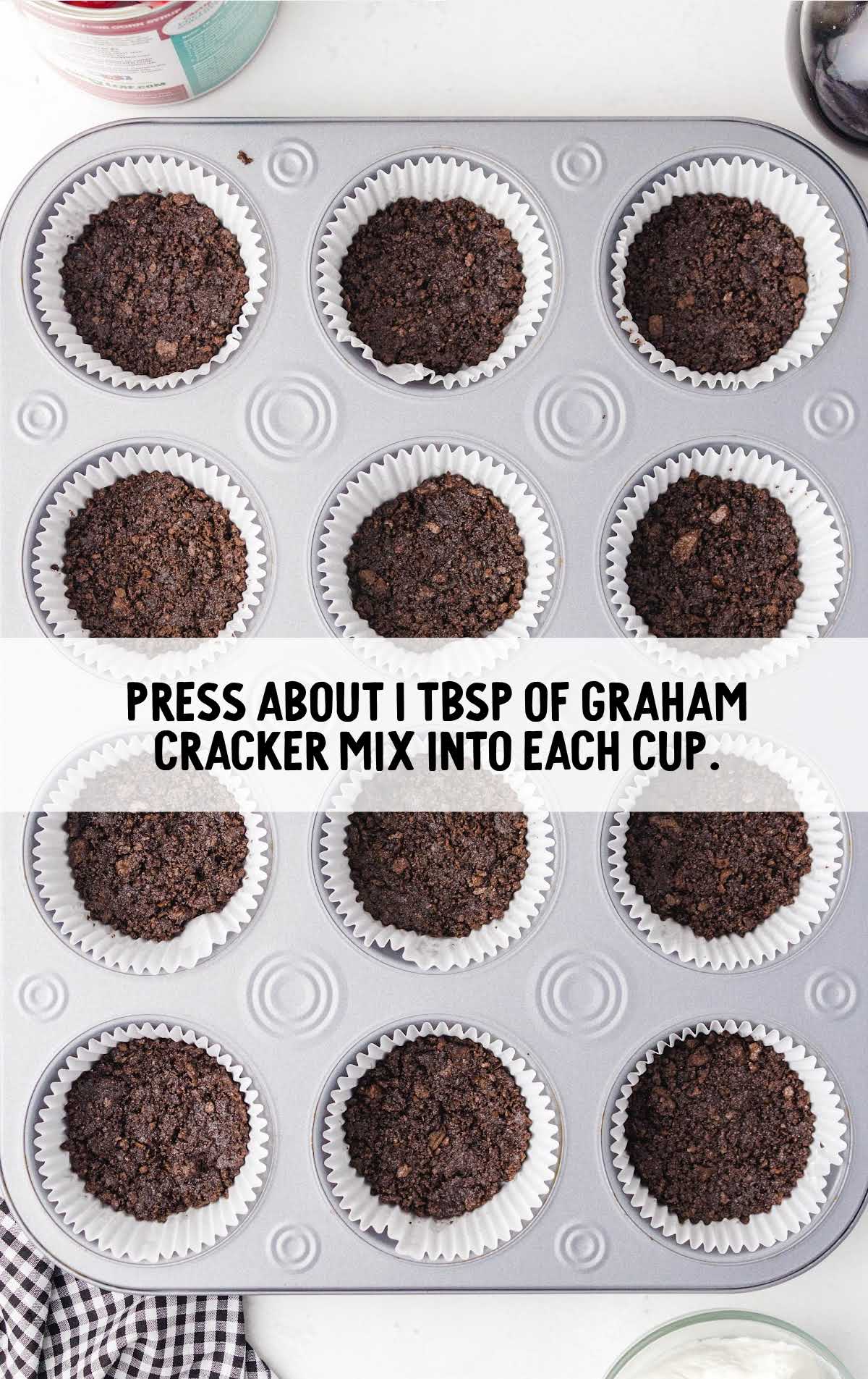 graham cracker added to the cupcake wrappers in a muffin pan