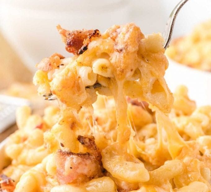 close up shot of bacon mac and cheese being picked up with a fork from a bowl